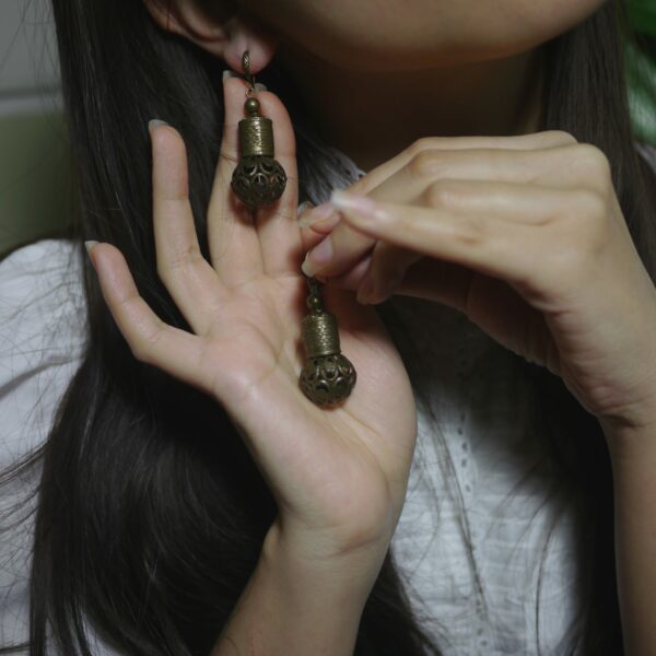 Photo de boucles d'oreilles chinoises de laiton style années 20 fait maison portées par une femme.