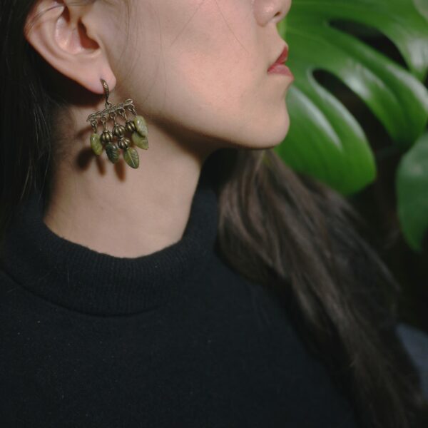 Photo de boucles d'oreilles de créateur français style art nouveau faites de calcédoine verte et de laiton, portées par un modèle.
