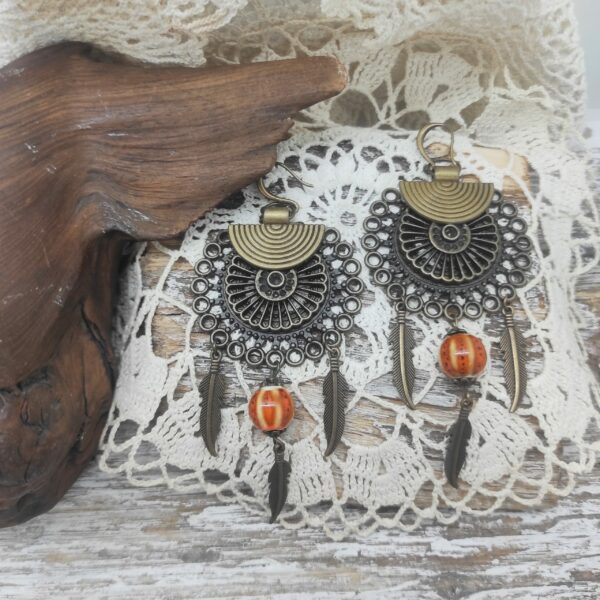 Photo d'une paire de boucles d'oreilles de créateur en forme d'attrape-rêve faites avec des perles de céramique japonaises.