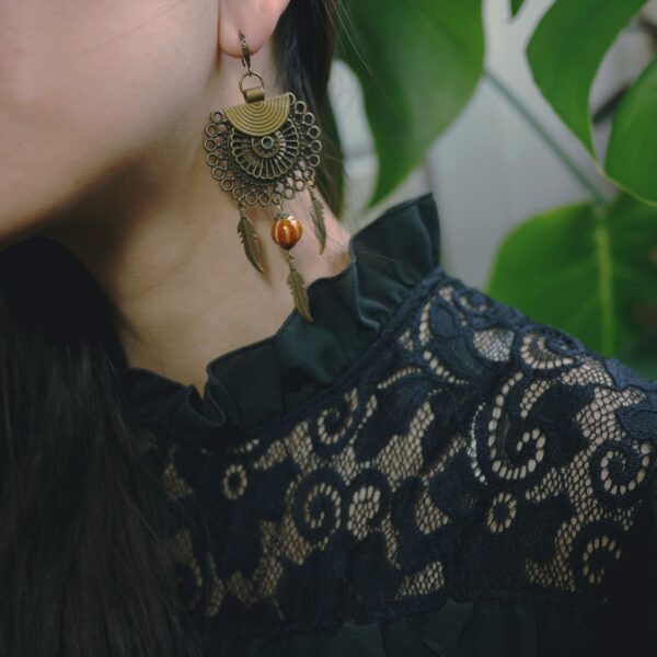 Photo d'une boucle d'oreille ethnique d'inspiration shaman et art déco faite main avec du laiton et des perles de céramique.