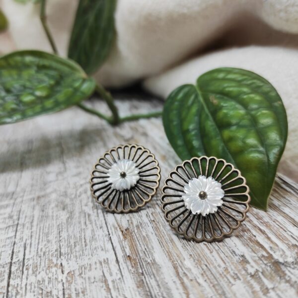 Photo rapprochée de boucles d'oreilles artisanales d'inspiration vintage et coréenne et faites de fleurs de chrysanthèmes en pierres semi-précieuses de nacre blanche.