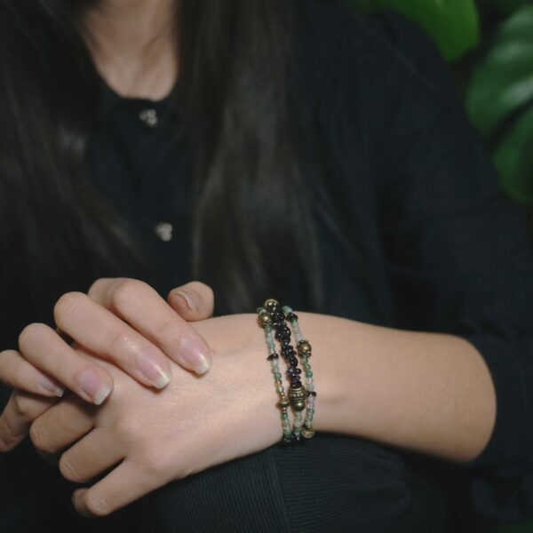 Photo d'un poignet de femme portant un bracelet original constitué de pierres semi-précieuses de grenat, d'agates et de laiton.