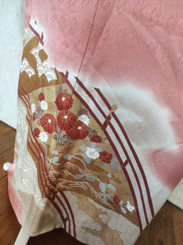 Photo du bas du kimono représentant un pont japonais remplis de fleurs asiatiques, le tout peint sur soierie