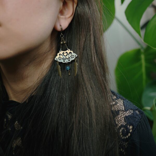 Modèle photo qui porte une boucle d'oreille vintage d'inspiration chinoise faite avec de la nacre blanche gravée et une perle d'agate.