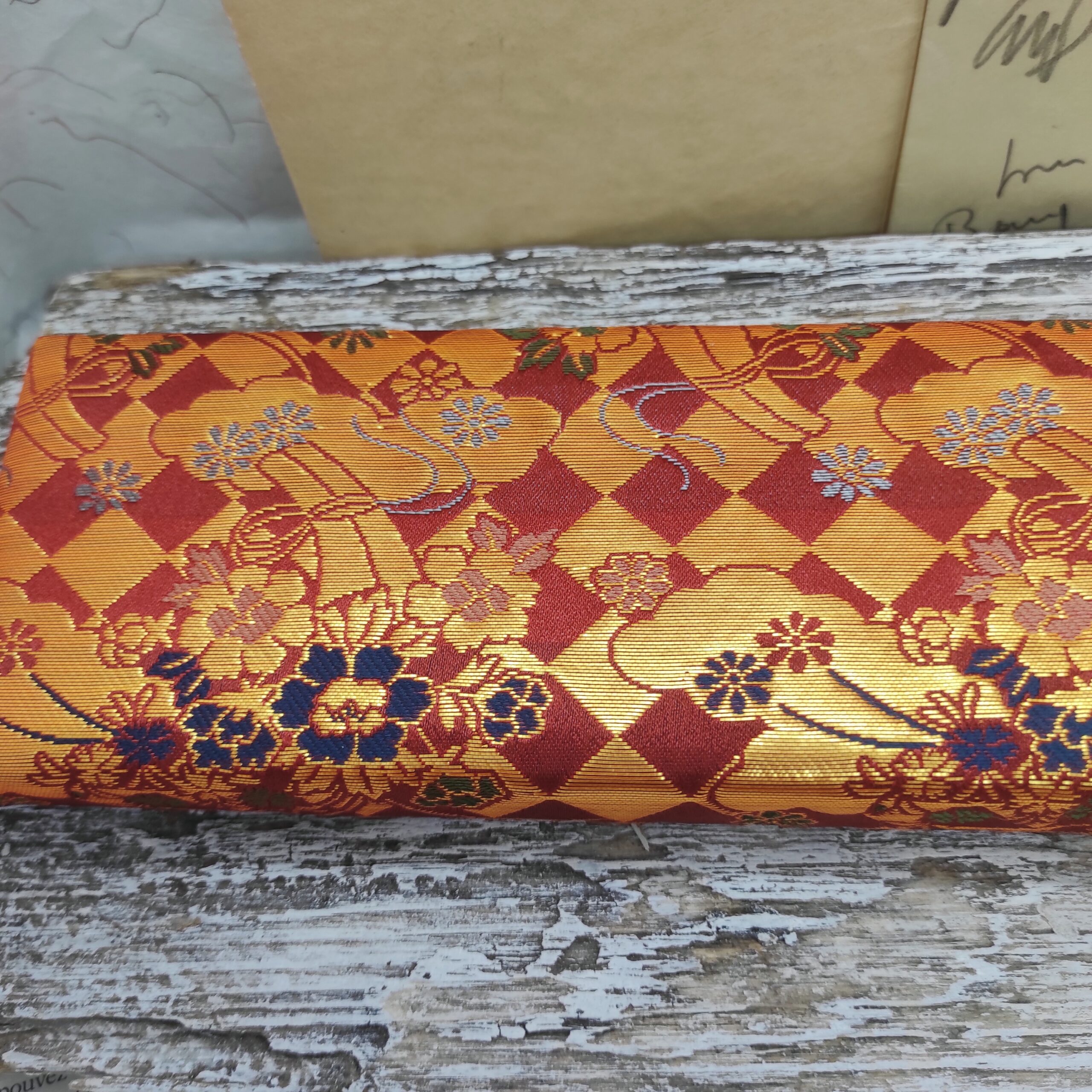 Photo close-up d'une pochette japonaise ancienne chinée en friperie. Motif de nuages, de fleurs et de losanges rouges