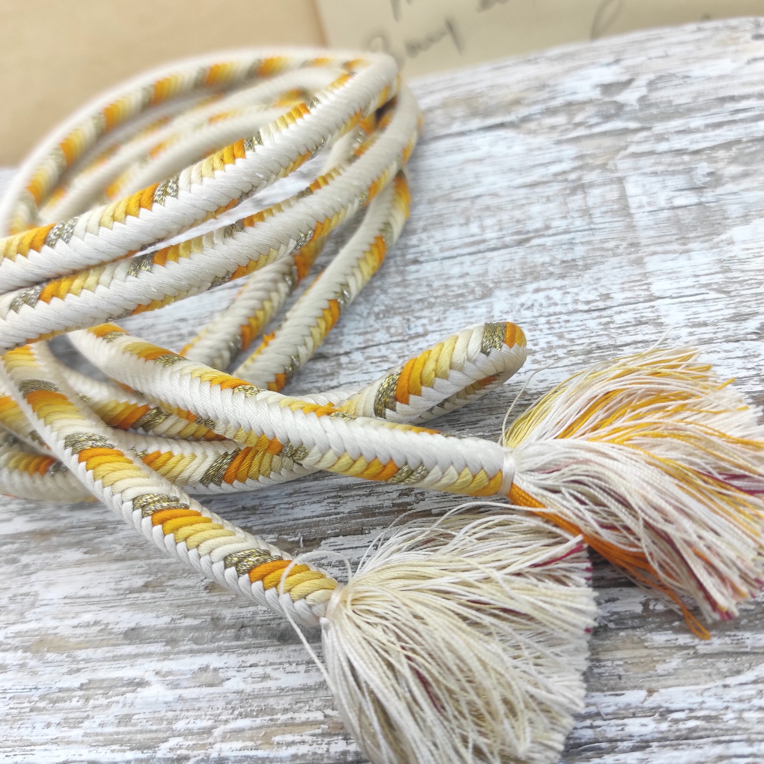 Photo détaillée des pompons d'un obijime japonais de couleur crème, orange et or