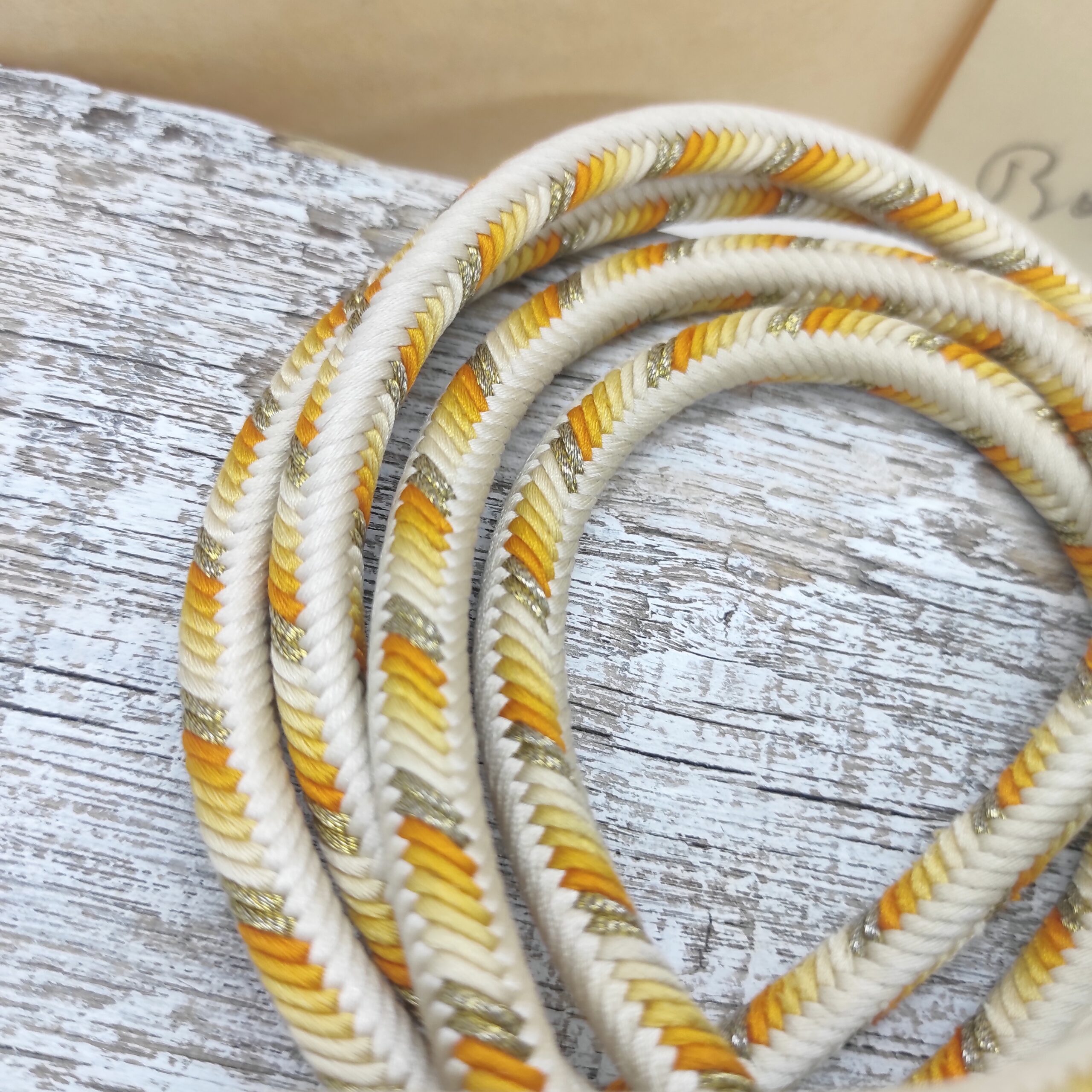Détail du cordon de soie d'un obijime crème et orange, tressé à la main par un artisan japonais qualifié