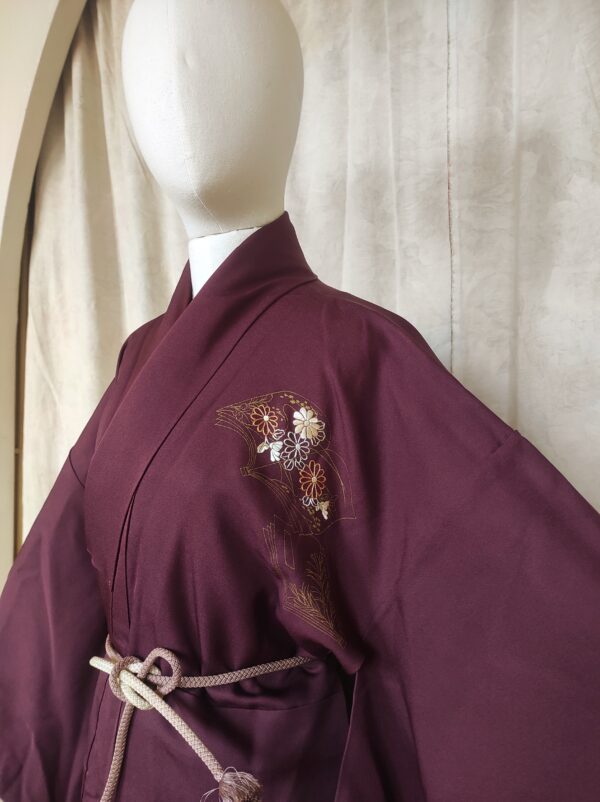 Photo rapprochée du kimono violet comportant un motif de livre brodé de fil d'or et de fleurs japonaises