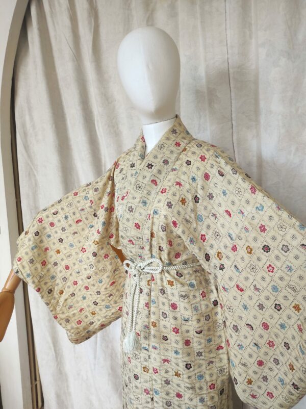 Photo rapprochée d'un mannequin portant un kimono japonais de couleur sable et ayant des motifs de blasons de samouraïs