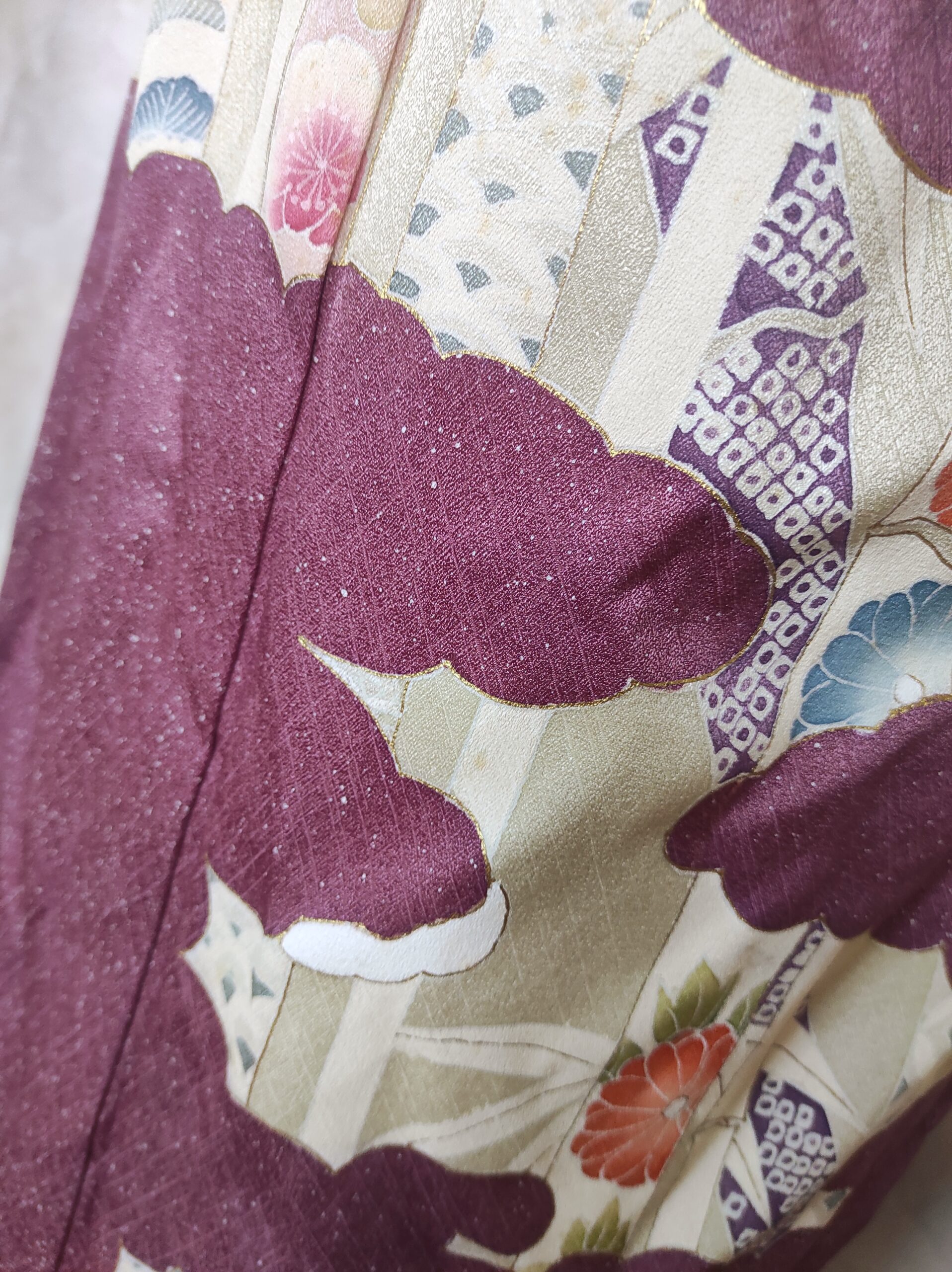Image rapprochée d'un pan de kimono en soie violine sur lequel sont peints à la main des bambous et des fleurs