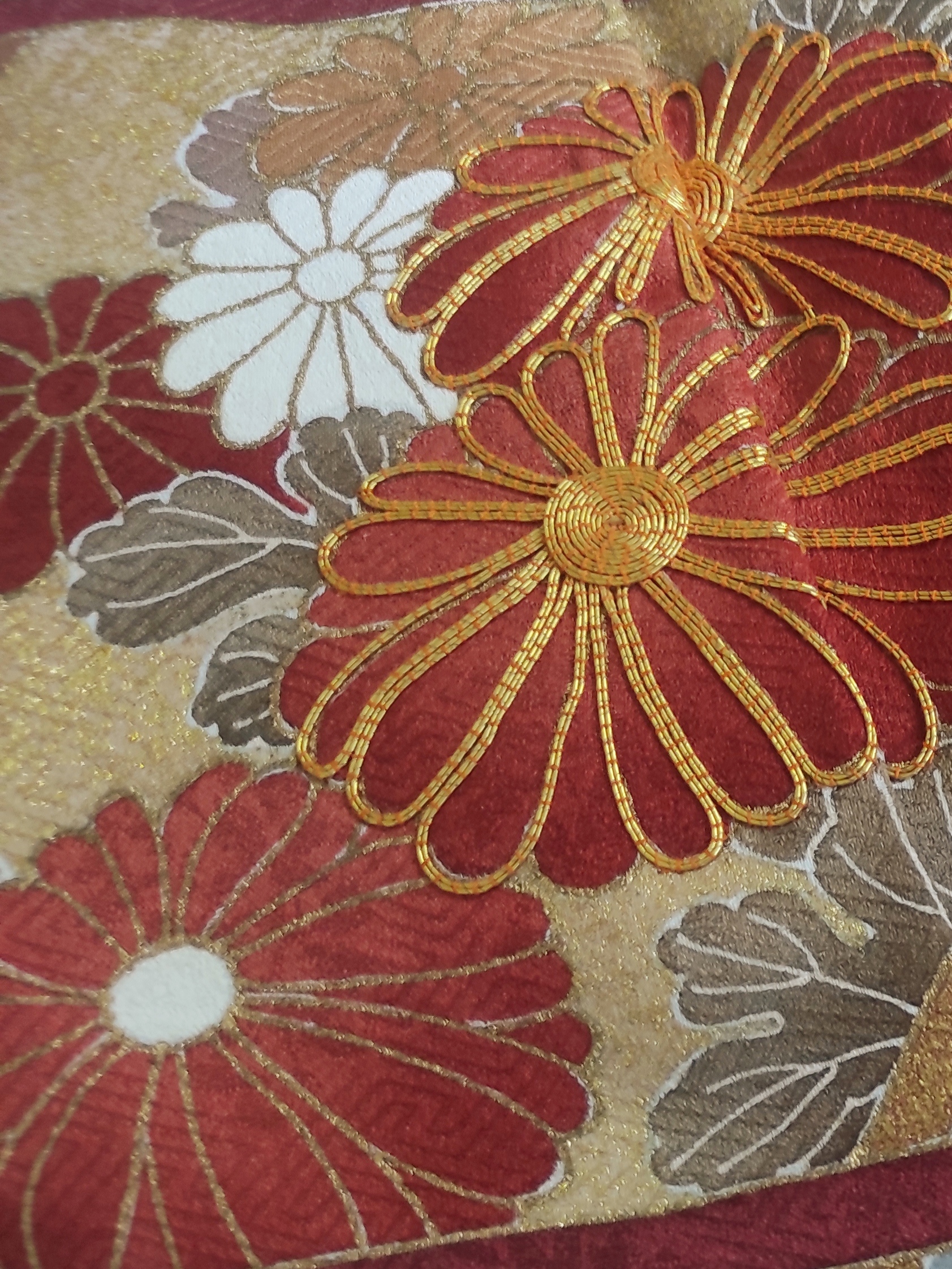 Photo rapprochée de fleurs de chrysanthèmes peintes sur soie et brodées à la main au fil d'or par technique de passementerie