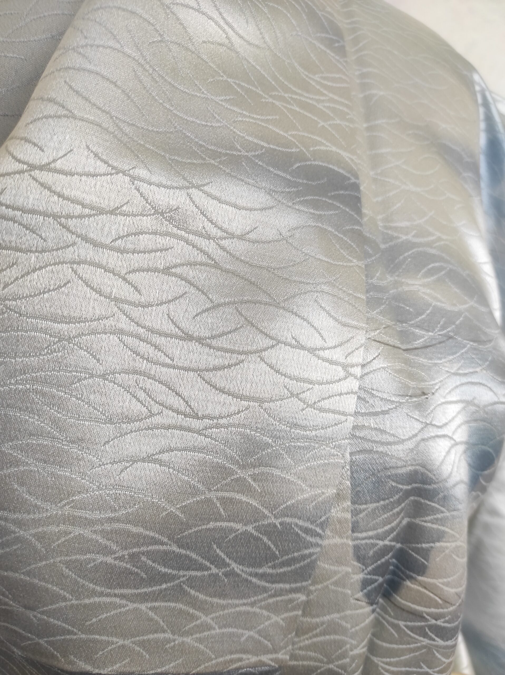 Photo rapprochée d'un kimono en soie bleu damassée avec tissage traditionnel au motif d'herbes