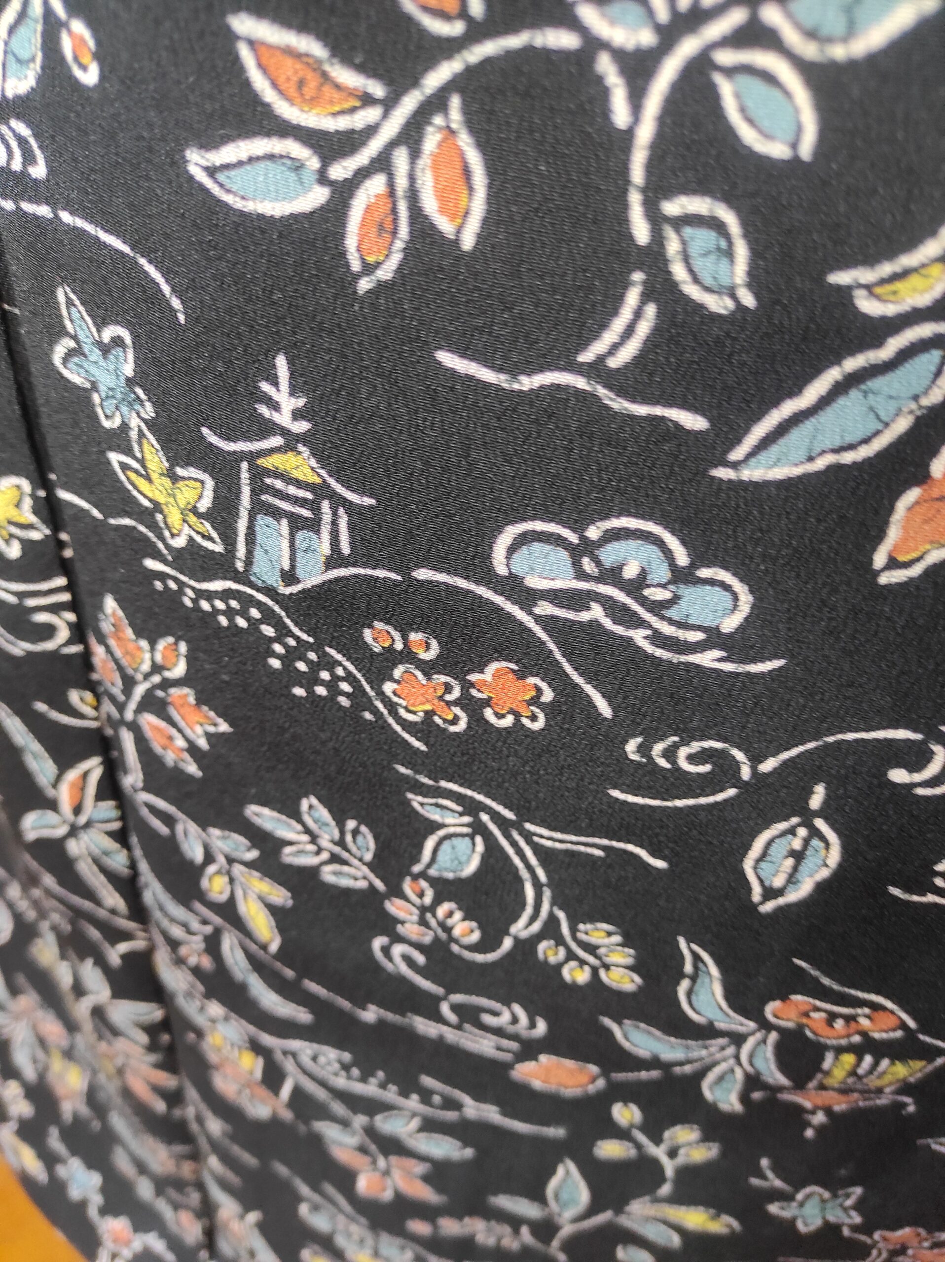 Image rapprochée d'un kimono de soie teintée en noir et de peintures faites main représentant des temples et végétaux