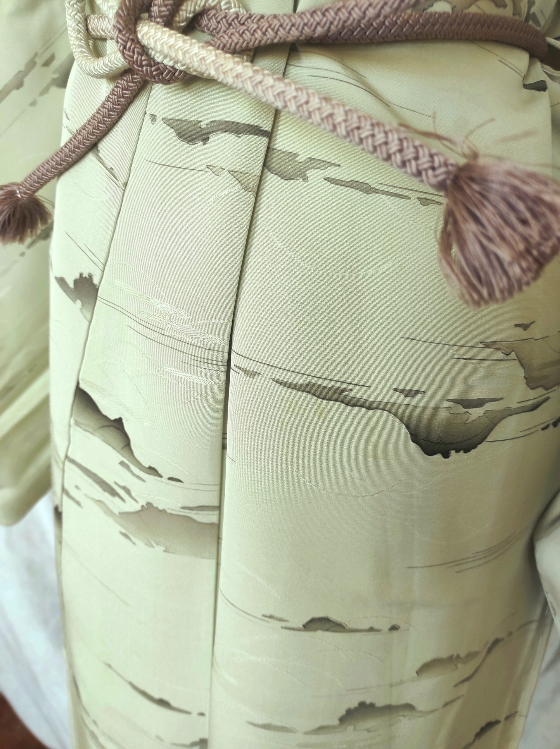 Image rapprochée du bas d'un kimono de soie vert comportant des peintures réalisées à la main par un artisan japonais