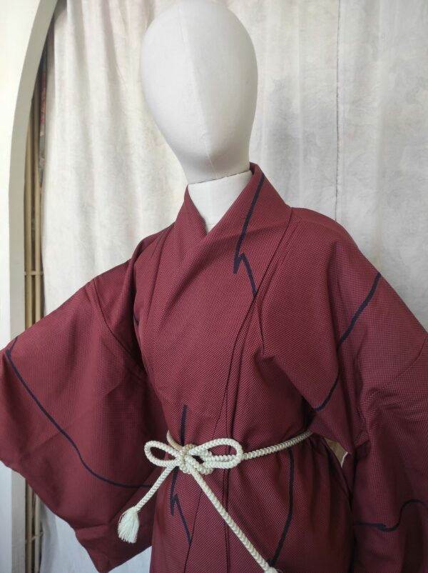 Photo du haut d'un kimono japonais de soie rouge composé de petits carreaux et de motifs géométriques