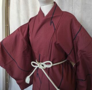 Photo du haut d'un kimono japonais de soie rouge composé de petits carreaux et de motifs géométriques