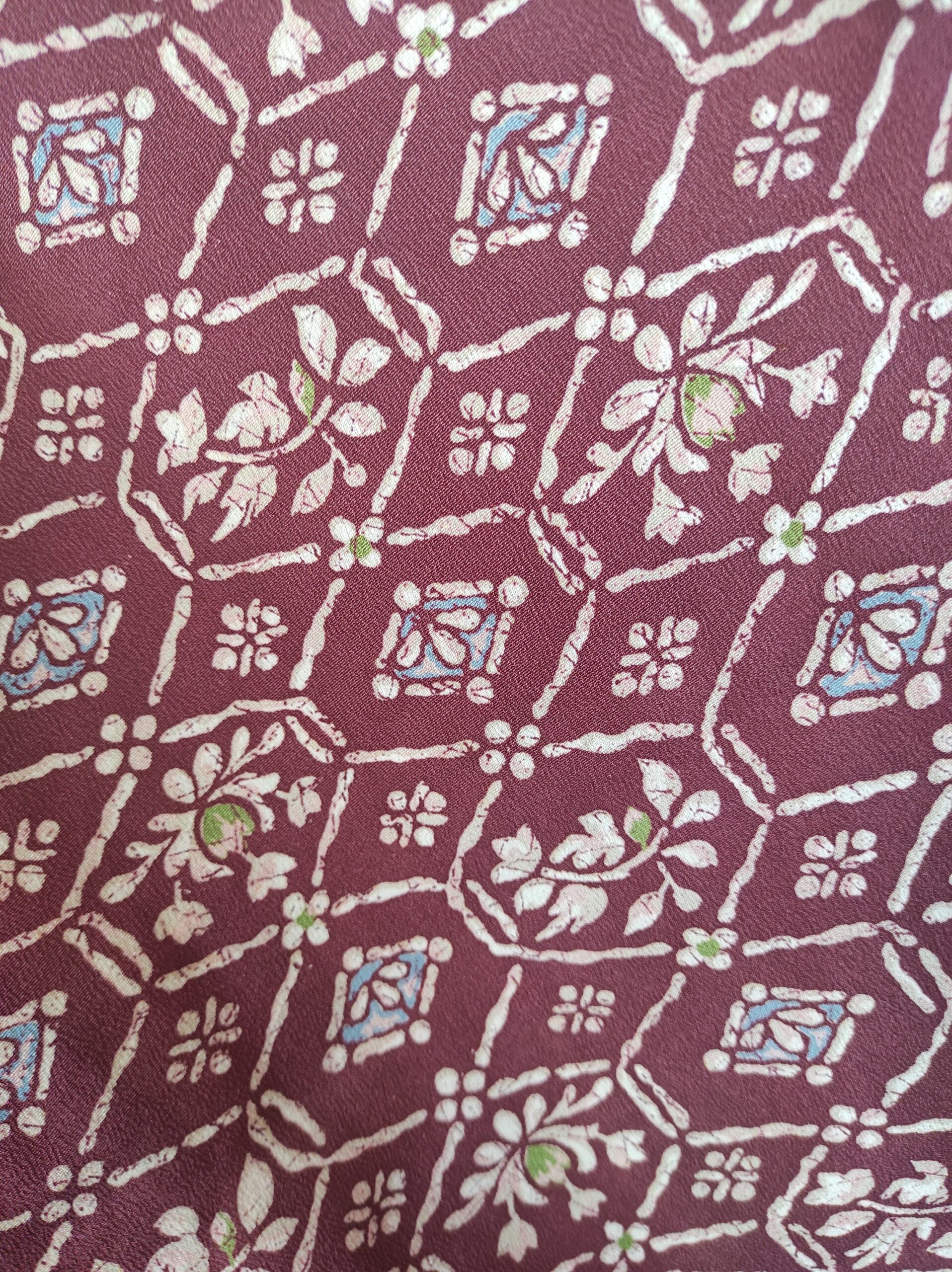 Photo rapprochée d'un motif baroque, géométrique et floral sur soie bordeaux rouge