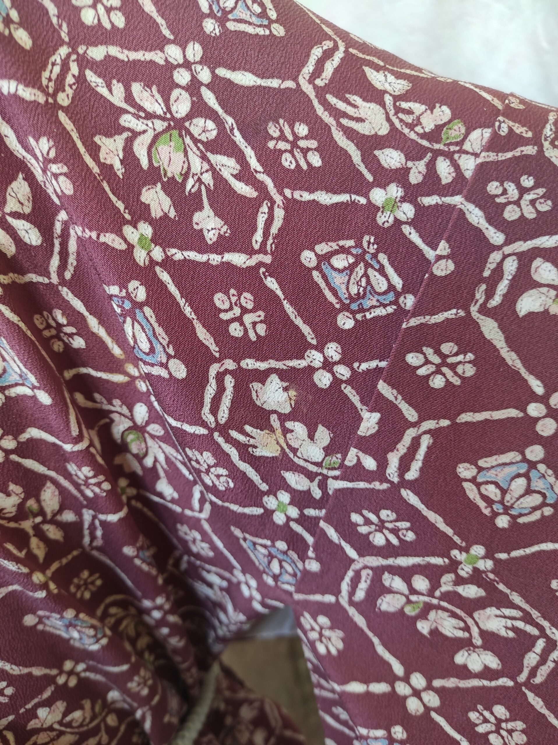 Photographie d'une manche de kimono japonais vintage de soie rouge sur lequel est peint un motif baroque