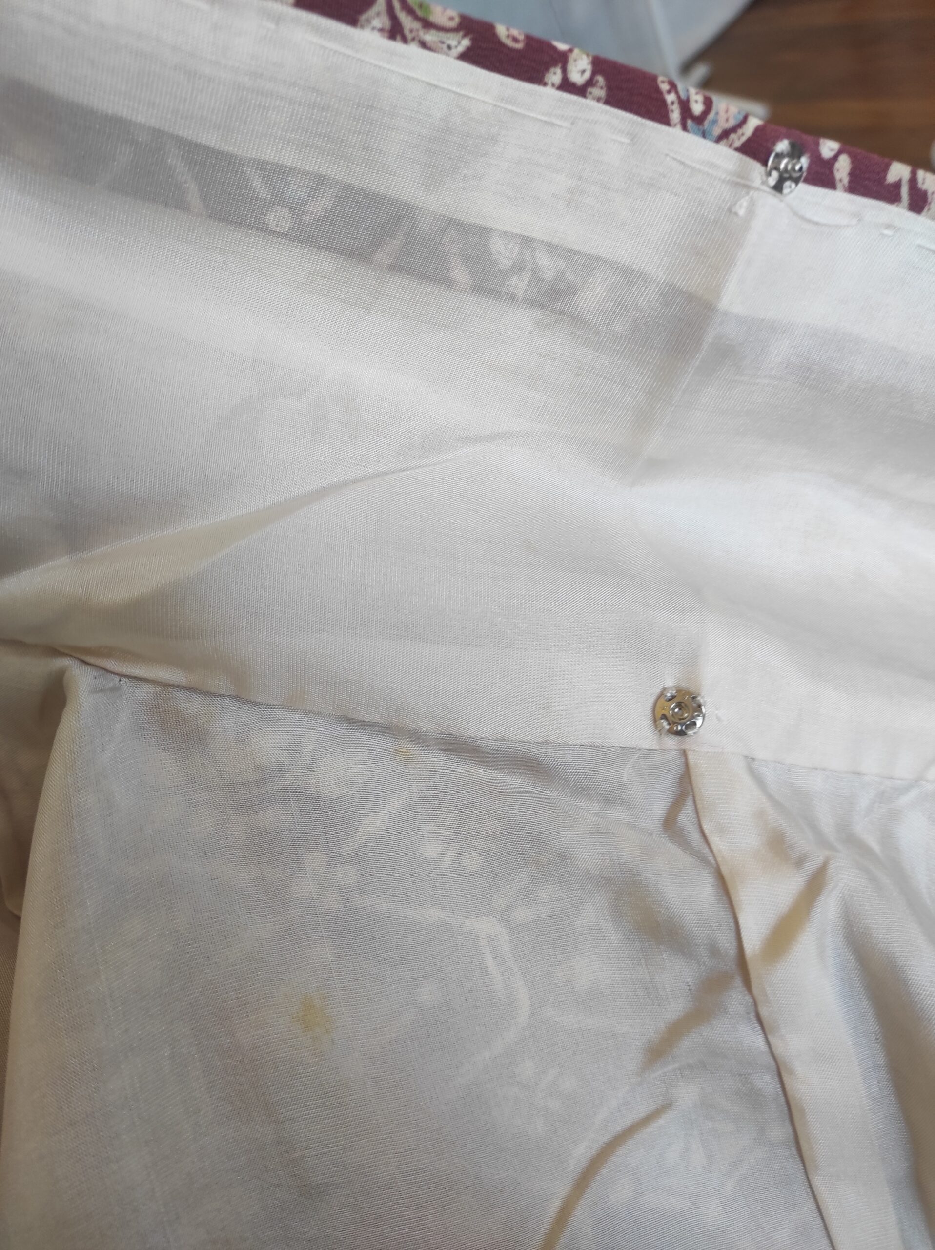 Photo du col d'un kimono de soie rouge et de sa doublure blanche contenant des boutons-pression