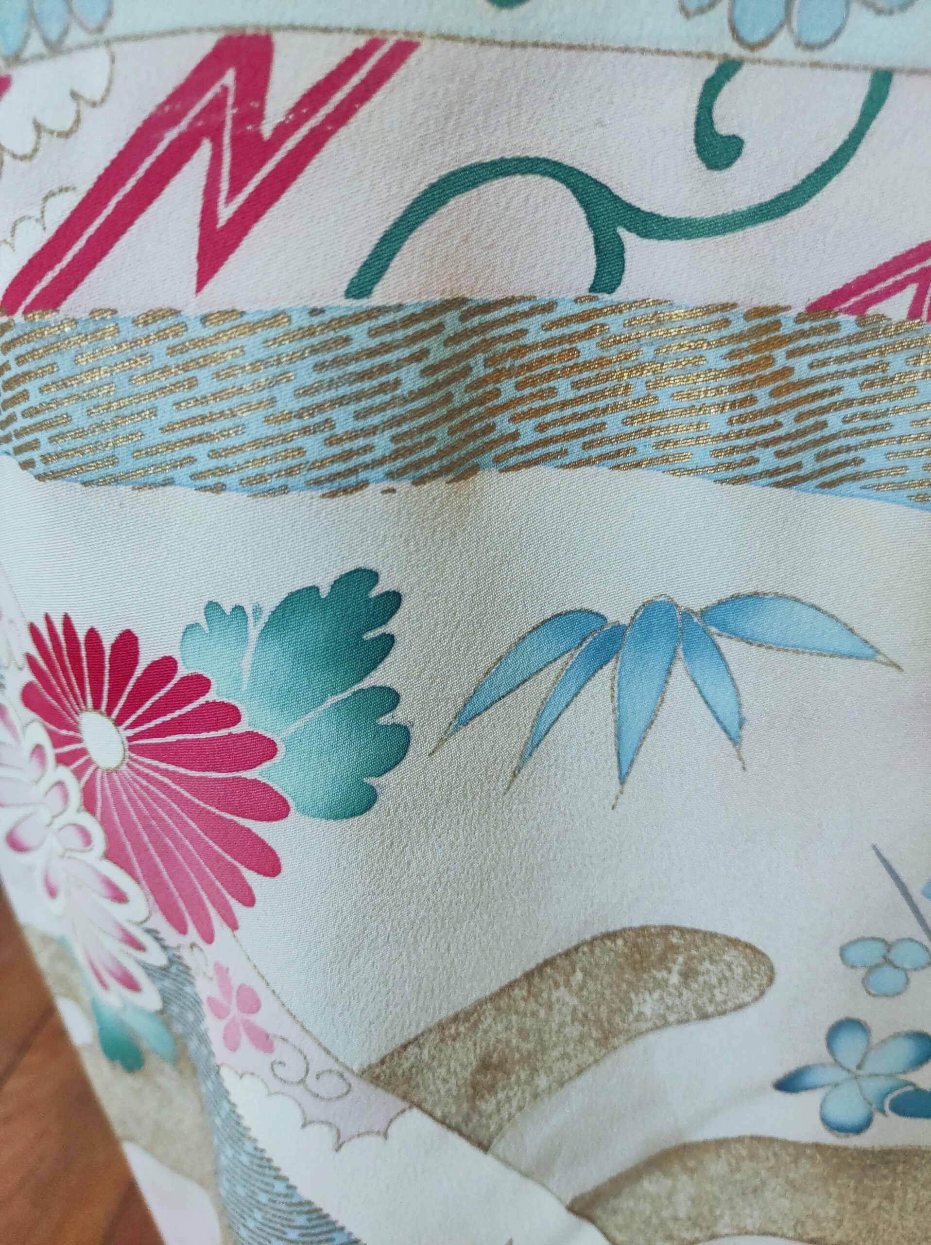 Photographie de détails d'un kimono en soie bleu comportant des peintures à l'or et des teintures florales