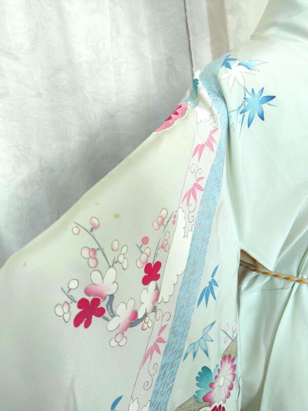 Photographie rapprochée de la manche d'un kimono de soie bleu comportant des motifs de sakura (fleurs de cerisier)