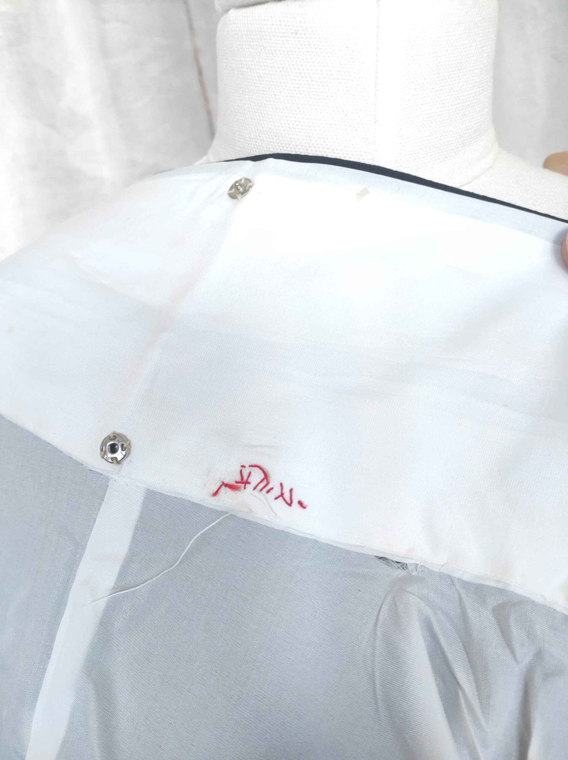 Photographie rapprochée de l'intérieur d'un kimono japonais vintage et du nom de l'artisan brodé à la main ainsi que de boutons-pression au col