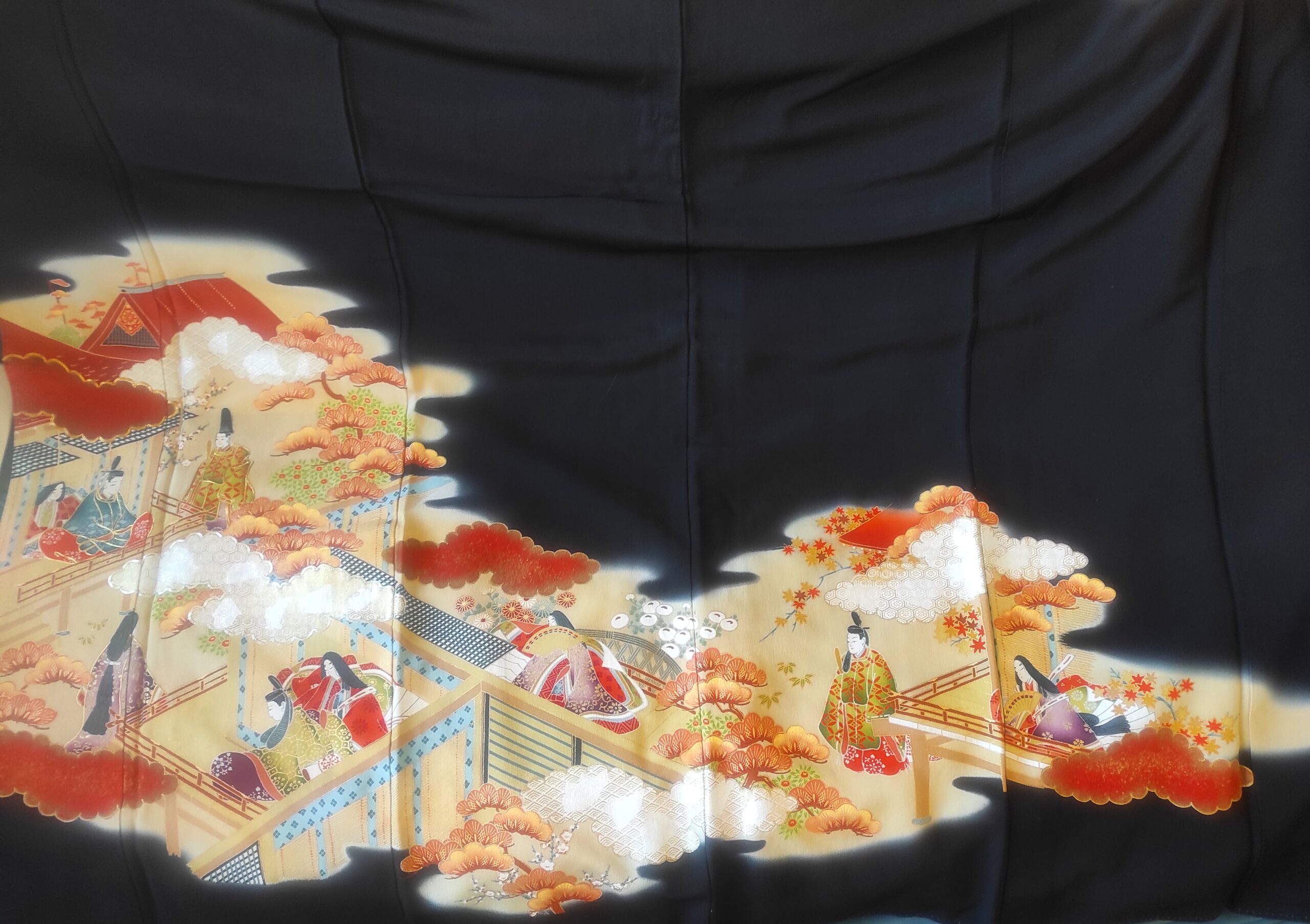 Photo d'un kimono japonais de soie noire étendu à plat pour exposer son paysage de ville traditionnelle