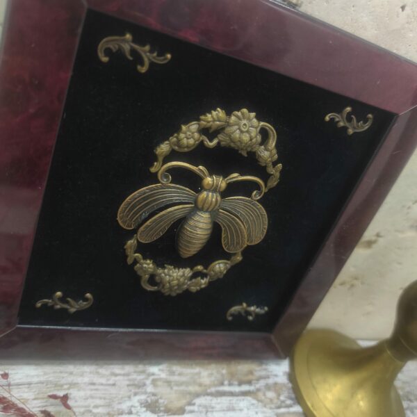Photo rapprochée d'une abeille en laiton bronze de style art déco avec des fleurs.