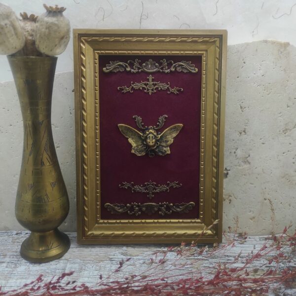 Photo générale d'un tableau recyclé avec fond en velours rouge comportant une femme papillon.