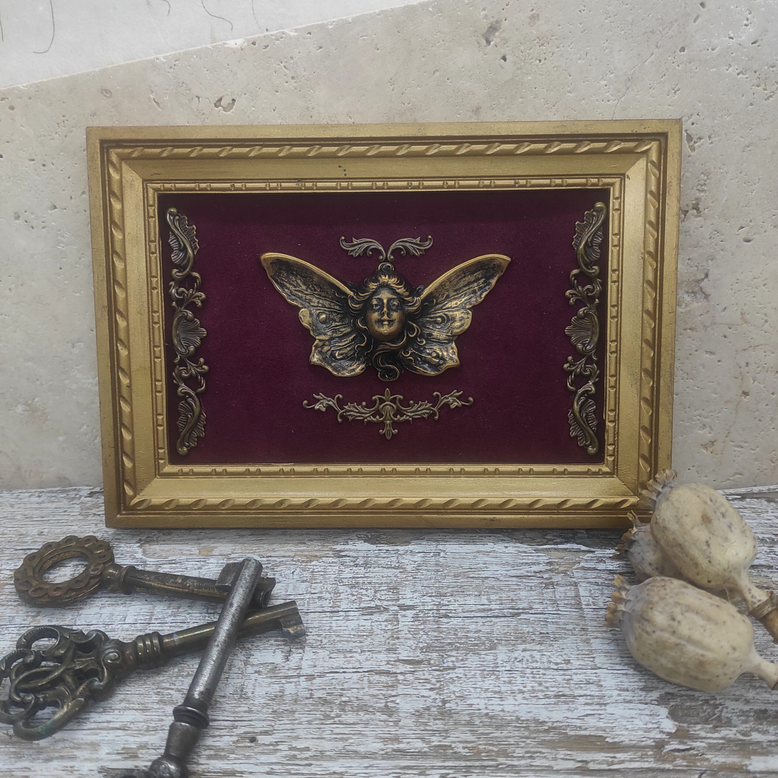 Photographie d'un cadre photo vintage recyclé comportant une femme papillon en laiton.