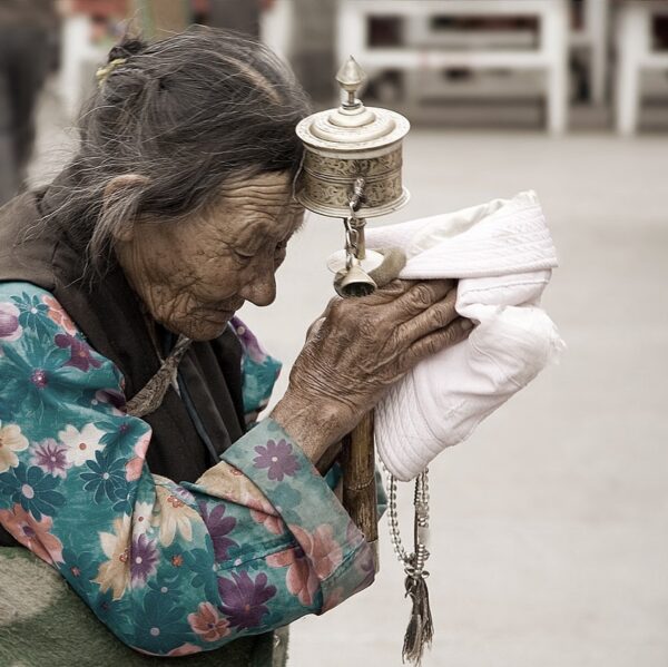 Photo d'une tibétaine avec un moulin à prières